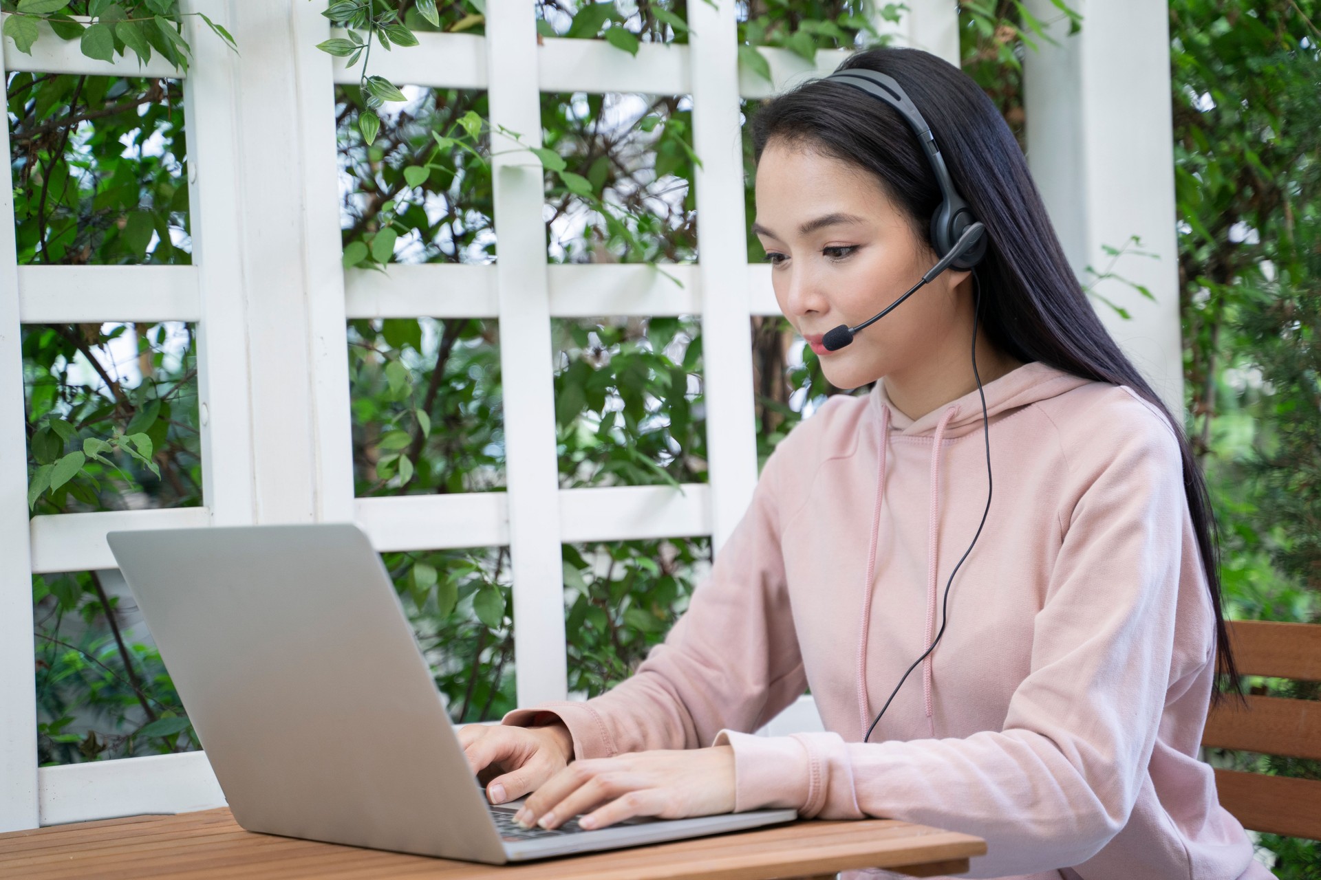 A young Asian lady is sitting learning online at the table at home.